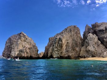 Rock formations in sea against clear blue sky