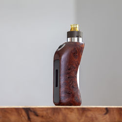 Close-up of old bottle on table against wall