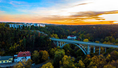 Bridge over river amidst buildings against sky during sunset