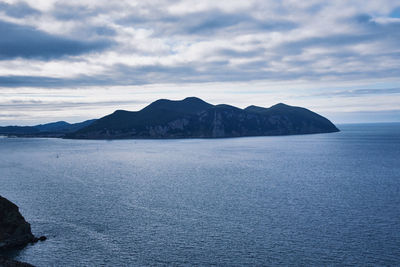 Scenic view of sea and mountains against sky