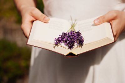 Midsection of woman holding purple flowering plant