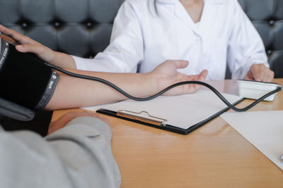 Midsection of man using mobile phone while sitting on table