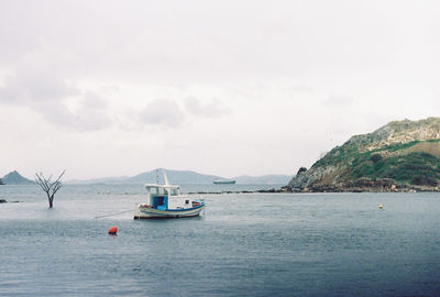 Boats in sea against cloudy sky