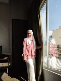 Portrait of smiling girl standing against window