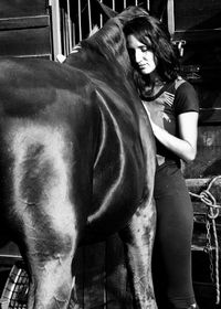Portrait of young woman with horse standing outdoors