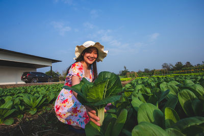 Portrait of smiling young woman on field against sky