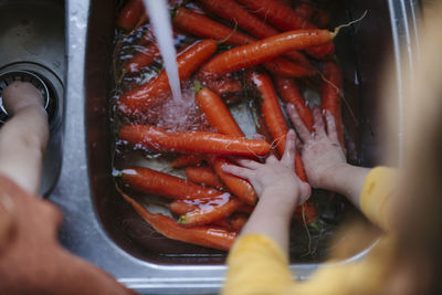 Girl washing carrots in kitchen sink