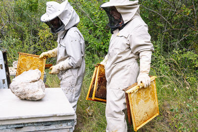 Male and female beekeepers working at farm