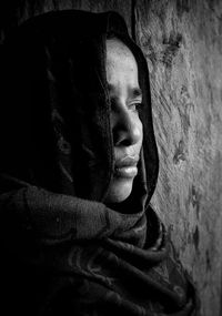 Portrait of young woman looking away against wall