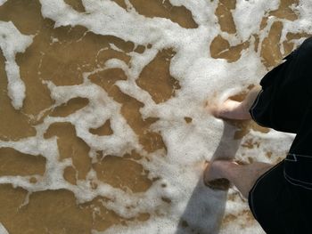 Low section of man standing in sea on shore