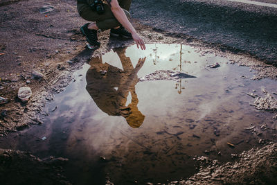 Low section of man standing on puddle