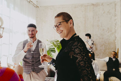 Smiling businesswoman holding wineglass while interacting with colleague during event at convention center