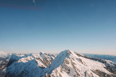 Aerial view of snowcapped mountains against blue sky