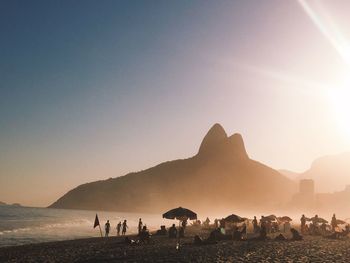 Group of people on beach against clear sky