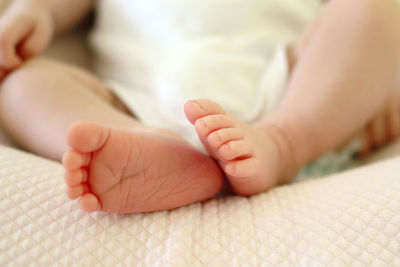 Low section of baby lying on bed