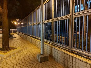 Illuminated street light on footpath by building at night