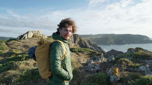 Man standing on rock by mountains against sky