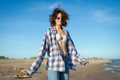 Young woman standing on land against sky