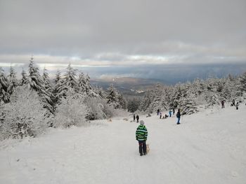 Rear view of people on snow covered mountain against sky