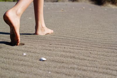 Low section of woman walking on sand at beach