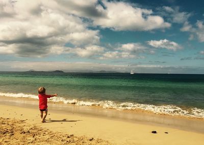 Boy walking on shore of beach 