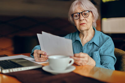 Senior businesswoman examining paper documents in cafe