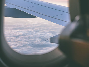 Cropped image of airplane flying over clouds