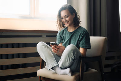 Young woman using laptop while sitting on sofa at home