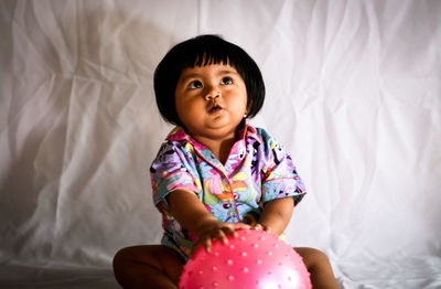 Cute girl sitting against curtain at home