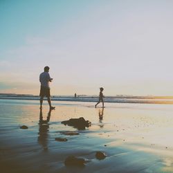 Man on beach against sky during sunset