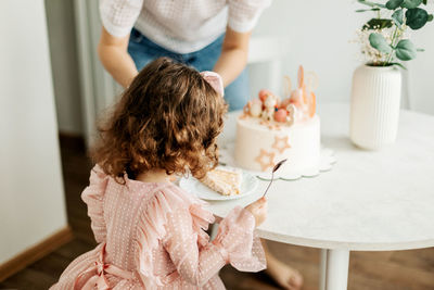 Mom cuts a piece of cake for her daughter during a birthday celebration at home