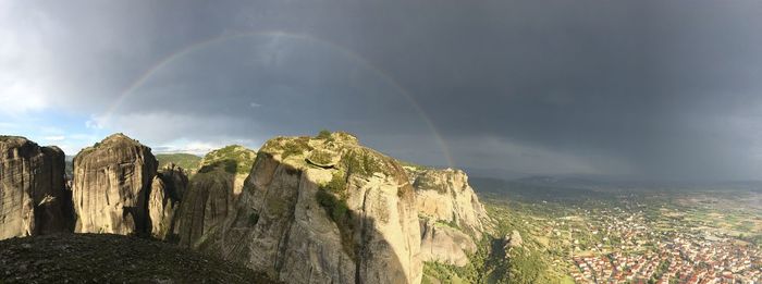 Panoramic view of rainbow over rocks against sky