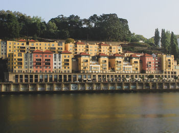 Buildings by river against sky in city