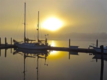 Sailboats in sea at sunset