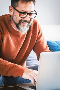 Young man using laptop while sitting on sofa at home