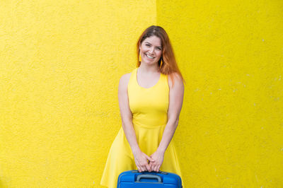 Portrait of smiling woman standing against yellow wall