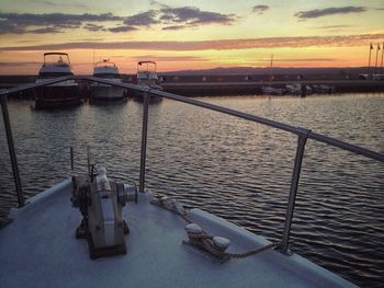 Boats moored in river against sky during sunset