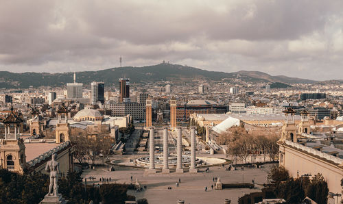 High angle view of city buildings against cloudy sky