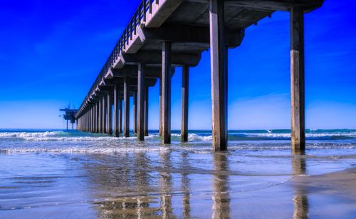 Pier on sea against blue sky