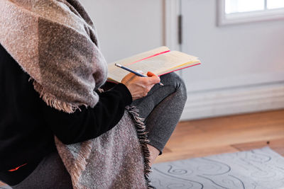 Midsection of woman reading book at home