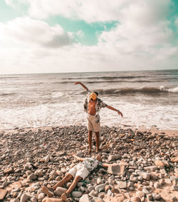 Full length of person with pebbles on beach against sky