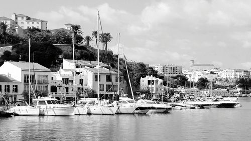 Sailboats moored in harbor against buildings in city