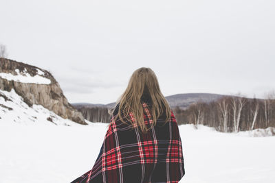 Woman on snow covered landscape against sky