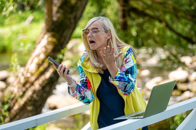 Senior emotional woman with laptop making video call and actively gesturing, online communication