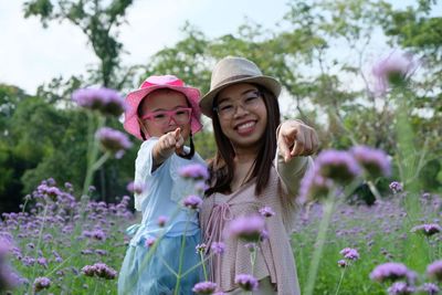 Portrait of beautiful woman with pink flowers against plants