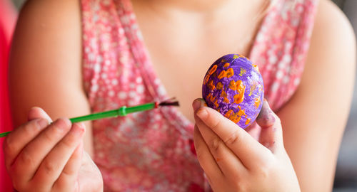 Midsection of little girl painting easter egg