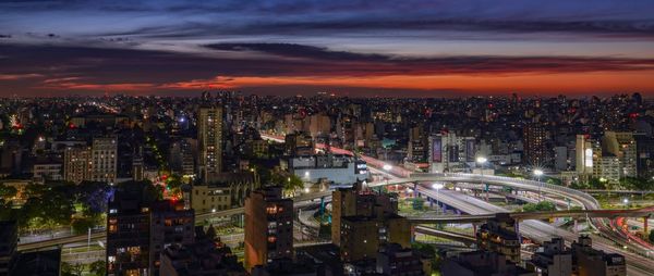 High angle view of illuminated cityscape against sky at sunset