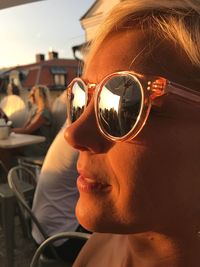 Close-up of woman wearing sunglasses at outdoor cafe during sunset