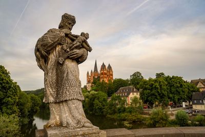 Statue against trees and building against sky