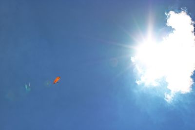 Low angle view of sun shining through clouds